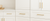 White kitchen cabinets with gold handles in a modern kitchen setting.